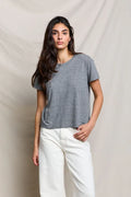 Woman wearing a gray t-shirt and white pants against a beige background